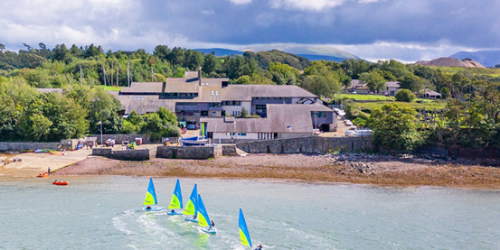 Aerial view over Plas Menai national outdoor centre with training dinghies heading out to sea.