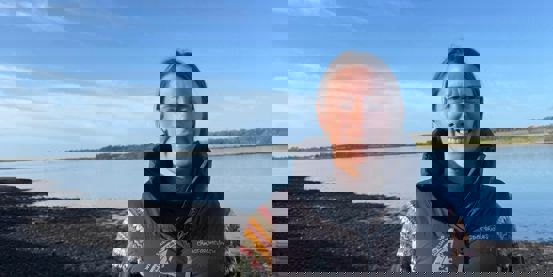 Sarah McGovern, RYA CW Chief Operation Officer, next to the water on Anglesey on a sunny winter day.