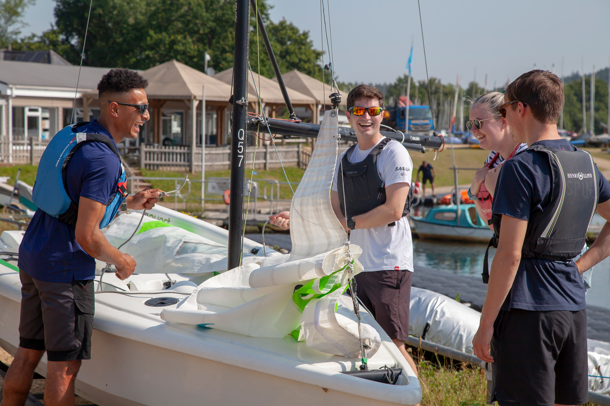 Long shot of four sailors laughing and preparing a sailboat