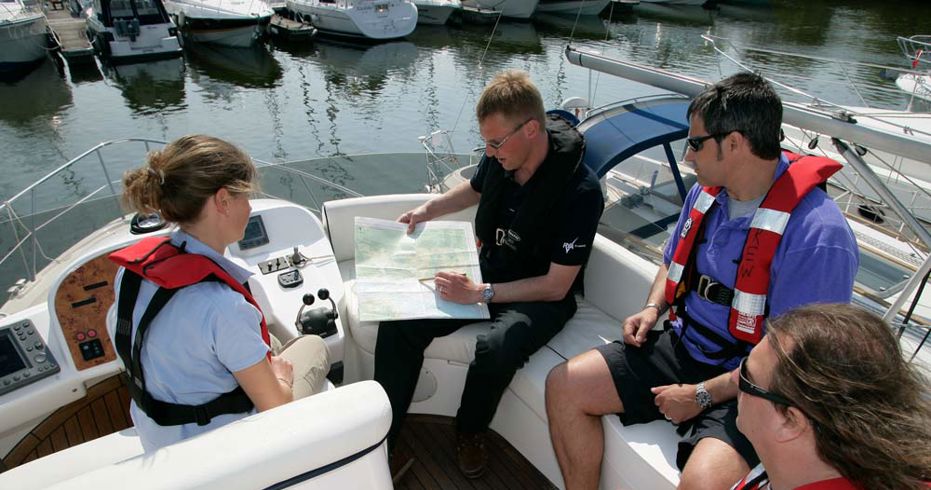 instructor holding a map and teaching whilst sitting on a motor cruiser